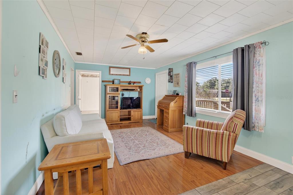 A living room features light blue walls, wood flooring, a white sofa, and a striped armchair — 2102 COLUMBUS DRIVE, BRANDON, FL