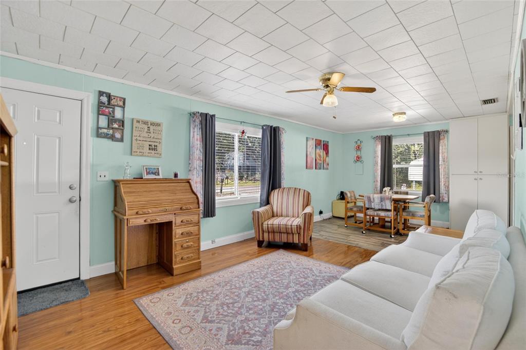 A living room with light blue walls, wood flooring, a white sofa, and a rolltop desk — 2102 COLUMBUS DRIVE, BRANDON, FL