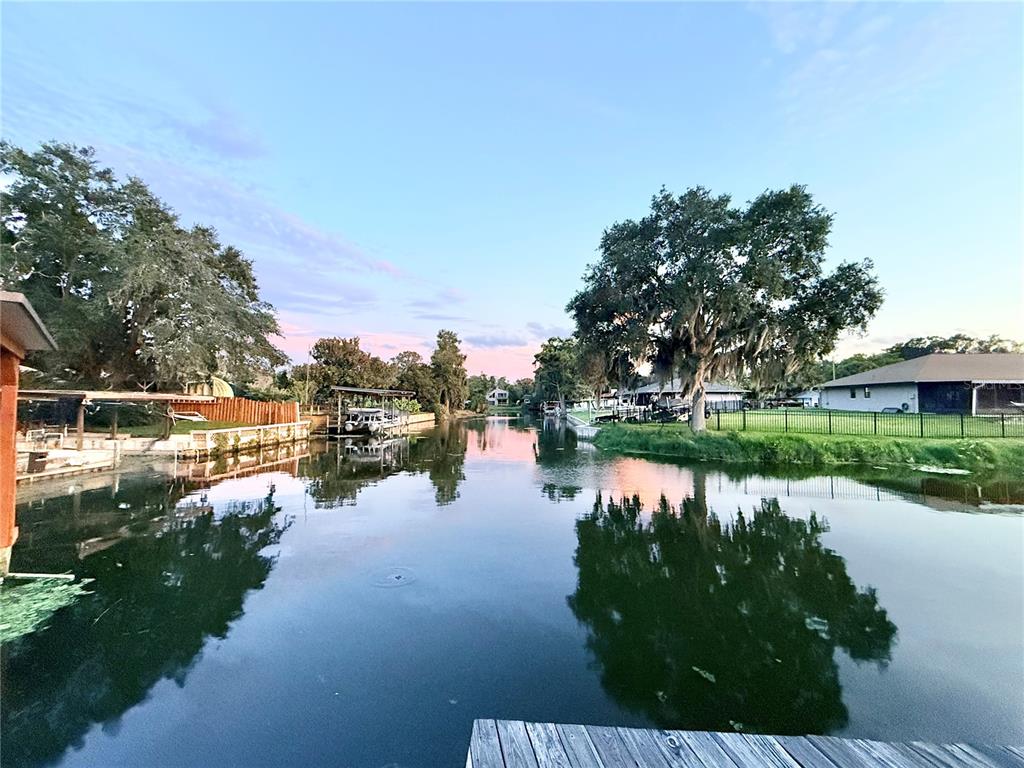 A view of a calm canal with boat docks, trees, and houses at sunset — 209 W DELAWARE STREET, TAVARES, FL