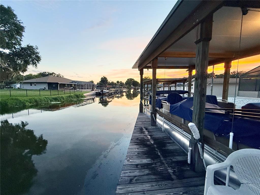 A wooden dock with a covered boat slip overlooks a canal at sunset — 209 W DELAWARE STREET, TAVARES, FL