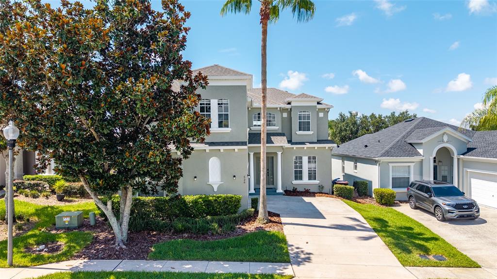 A two-story house with a gray exterior, a palm tree, and a driveway with a car — 526 PINELOCH DRIVE, HAINES CITY, FL