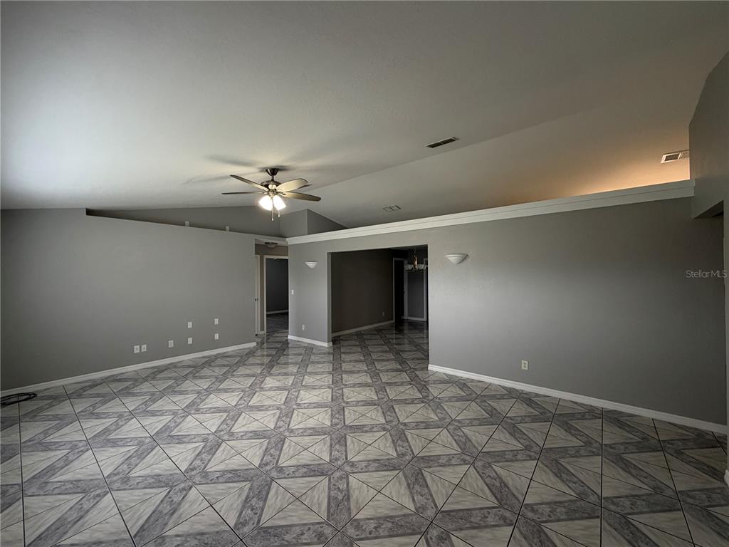 A spacious room with gray walls, a vaulted ceiling, and patterned tile flooring — 7750 SE 150 AVENUE, MORRISTON, FL