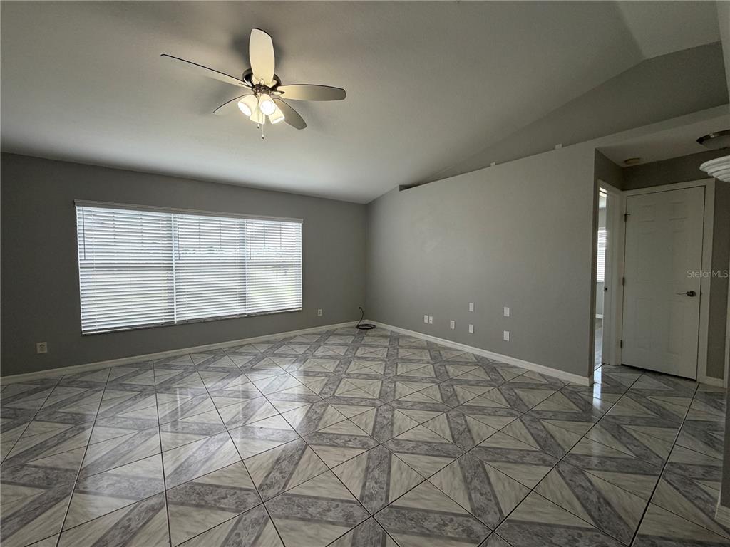 A living room features gray walls, a vaulted ceiling, a ceiling fan, and patterned tile flooring — 7750 SE 150 AVENUE, MORRISTON, FL
