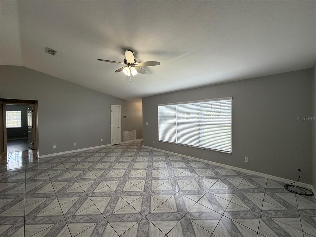 A spacious living room features gray walls, a vaulted ceiling, and patterned tile flooring — 7750 SE 150 AVENUE, MORRISTON, FL