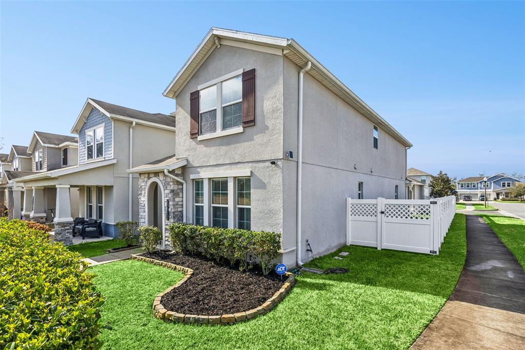 A two-story house with a stucco exterior, stone accents, and a white vinyl privacy fence — 10043 SEQUEL ALLEY, WINTER GARDEN, FL