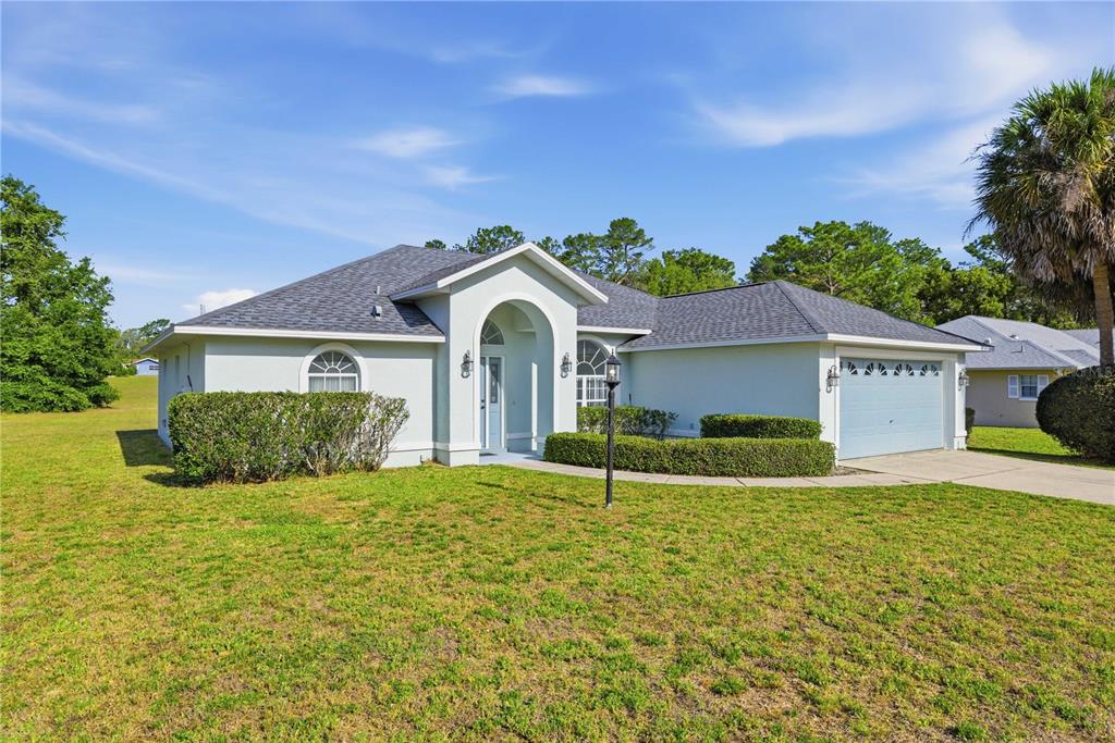 A single-story house with a light-colored exterior, arched entryway, and an attached two-car garage — 10772 SW 53RD CIRCLE, OCALA, FL