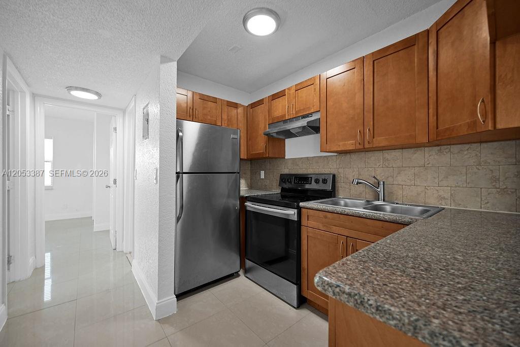 A kitchen features stainless steel appliances, wood cabinets, and granite countertops — 572 SW Kathy Ct, Margate FL 33068, MARGATE, FL