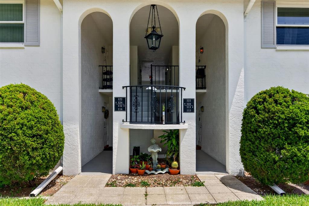 The exterior of a multi-unit residential building features arched entryways and a central stairwell — 5800 HOLLYWOOD BOULEVARD UNIT 112, SARASOTA, FL