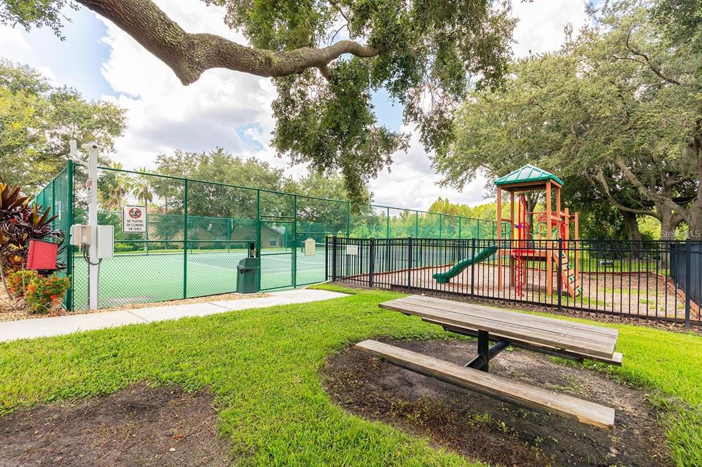 A picnic table sits on a grassy lawn near a fenced playground and tennis court — 2413 PRAIRIE VIEW, WINTER GARDEN, FL