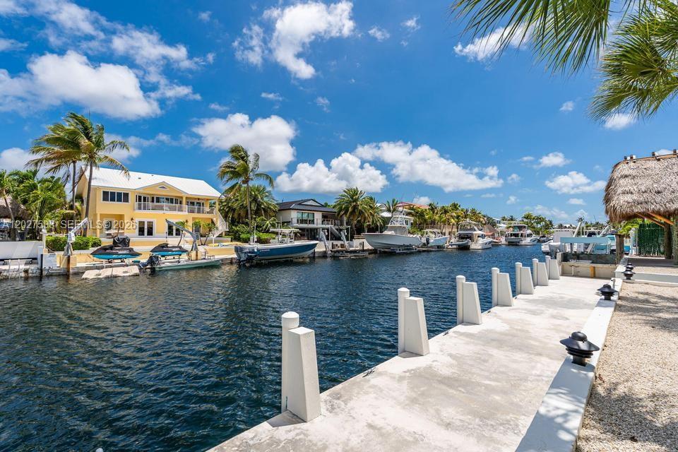 A canal view shows a concrete dock with white posts and several boats moored nearby — KEY LARGO, FL