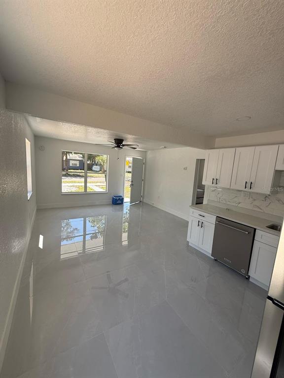An open-concept kitchen and living area with white cabinets, stainless steel appliances, and tile flooring — 427 40TH AVENUE S, ST PETERSBURG, FL