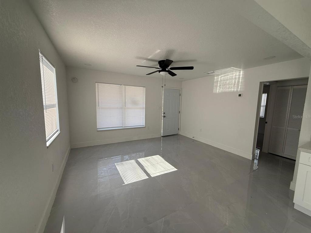 An empty room features white walls, a ceiling fan, and light-colored tile flooring — 427 40TH AVENUE S, ST PETERSBURG, FL