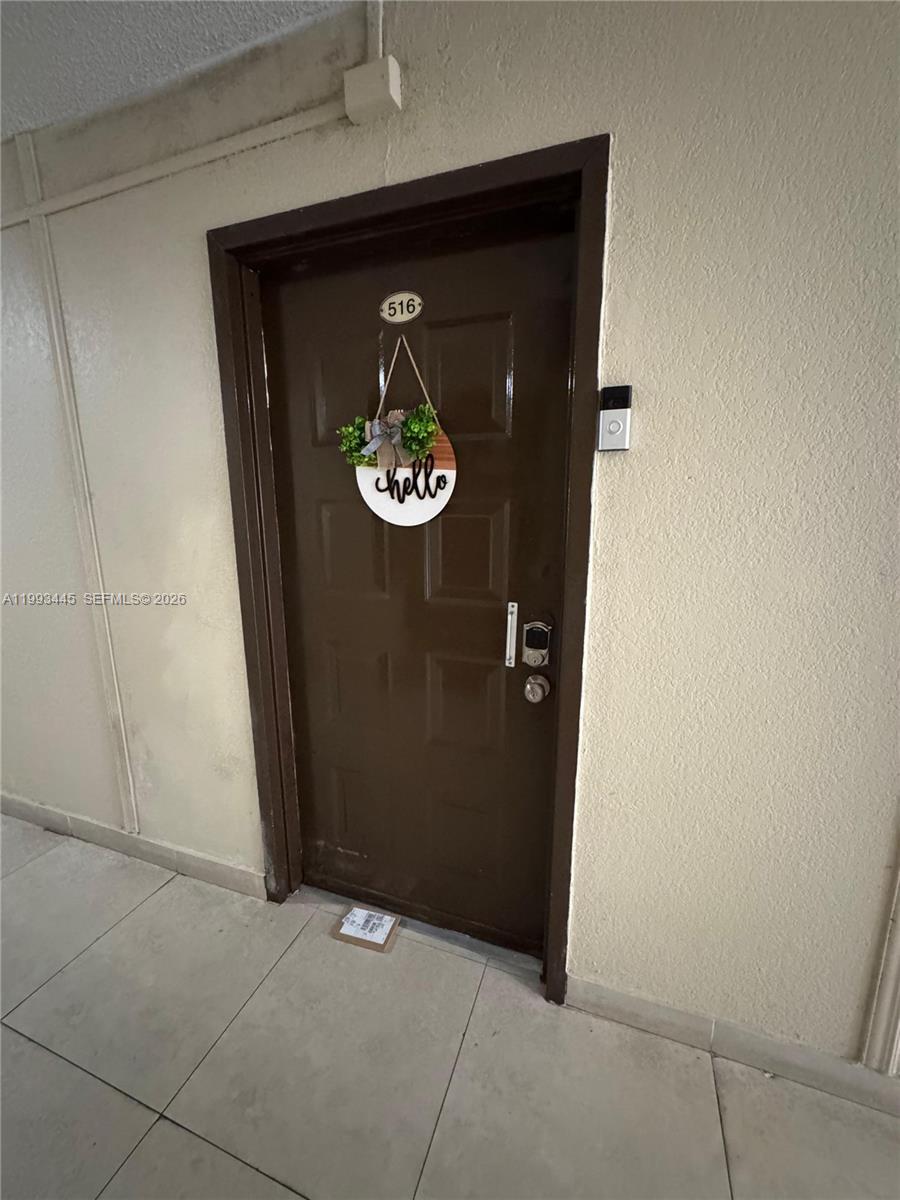 A brown apartment door with a decorative sign and a smart doorbell is shown — 6960 Miami Gardens Dr # 516, Hialeah FL 33015, HIALEAH, FL