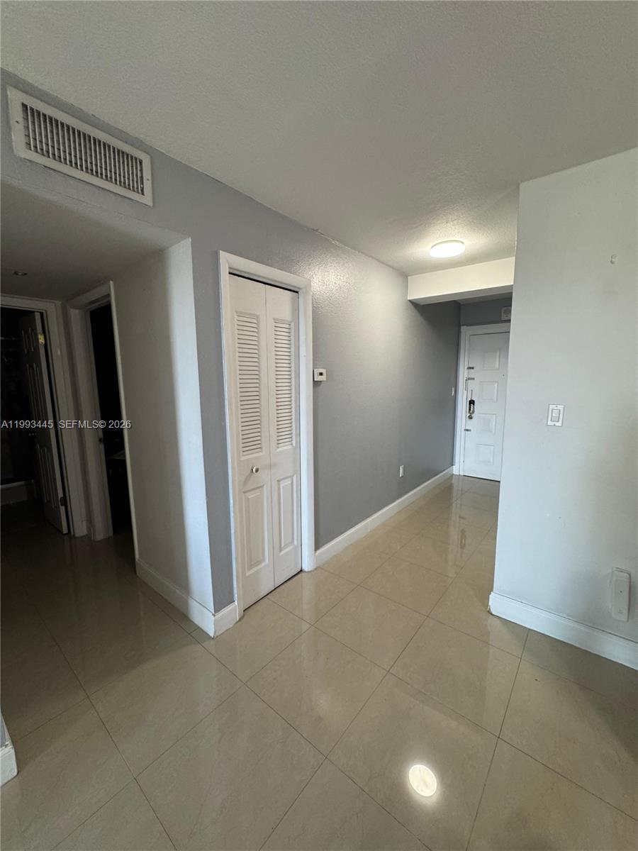A hallway with light-colored tile flooring, gray walls, and white doors — 6960 Miami Gardens Dr # 516, Hialeah FL 33015, HIALEAH, FL