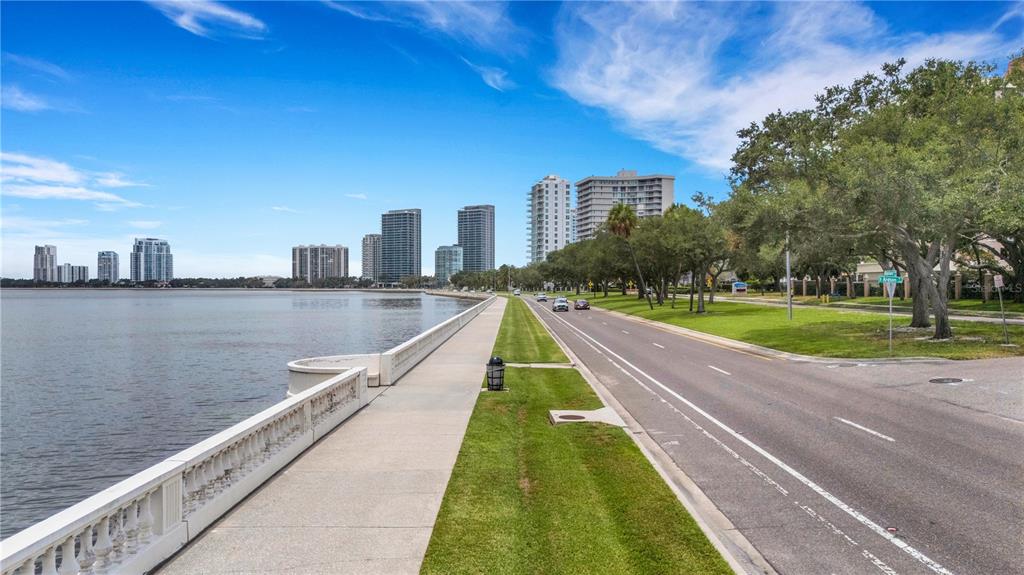 A paved sidewalk runs alongside a road and a waterfront wall with high-rise buildings nearby — 2403 S ARDSON PLACE UNIT 402B, TAMPA, FL
