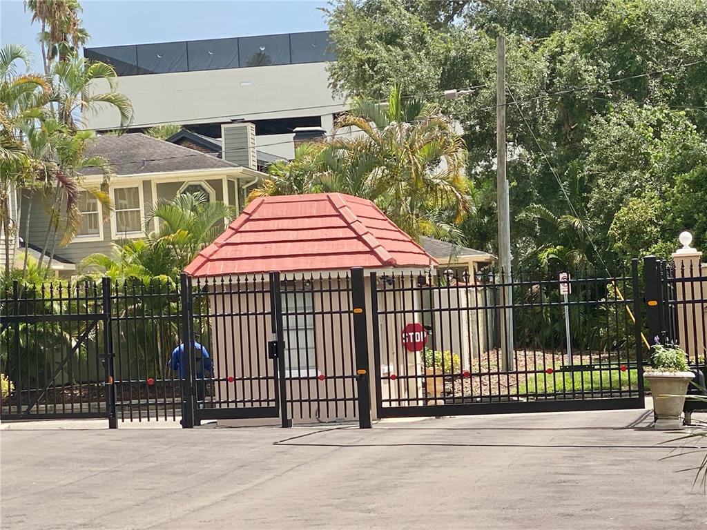 A gated entrance features a small guardhouse with a red tiled roof and black fencing — 2403 S ARDSON PLACE UNIT 402B, TAMPA, FL