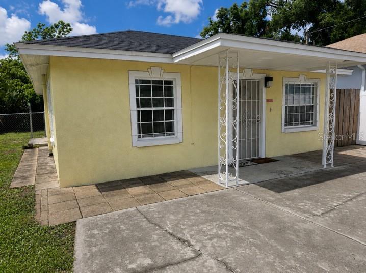A yellow house with a concrete driveway and a covered porch supported by decorative columns — 1807 E WATERS AVENUE, TAMPA, FL