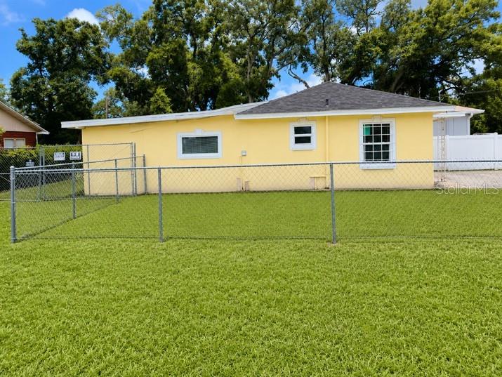 A yellow single-story house with a chain-link fence in the foreground — 1807 E WATERS AVENUE, TAMPA, FL