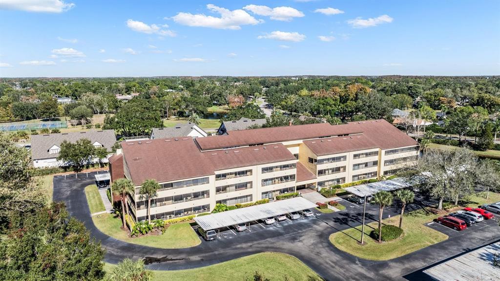 An aerial view shows a multi-story apartment building with a brown roof and covered parking — 13612 S VILLAGE DRIVE UNIT 5212, TAMPA, FL