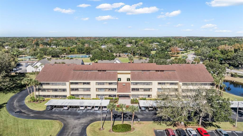 An aerial view shows a multi-story apartment building with a brown roof and parking carports — 13612 S VILLAGE DRIVE UNIT 5212, TAMPA, FL