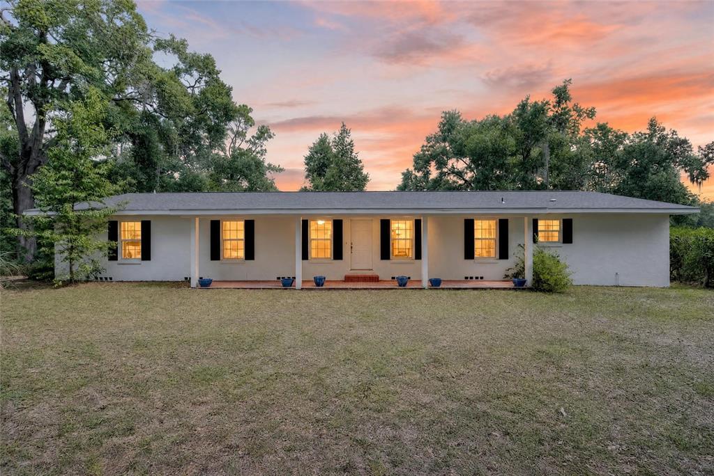 A single-story white house with black shutters and a front porch sits on a lawn — 7555 SW 77TH PLACE, OCALA, FL