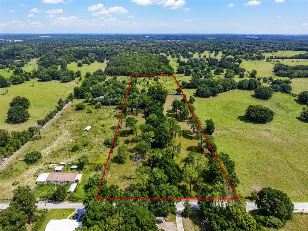 An aerial view shows a rectangular lot outlined in red amidst a rural, grassy landscape — 7555 SW 77TH PLACE, OCALA, FL