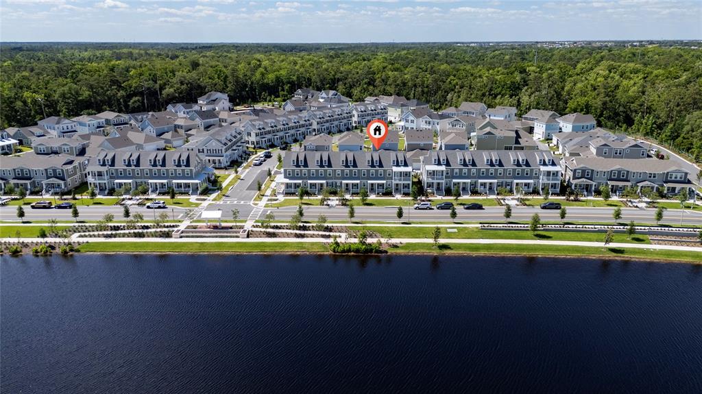 An aerial view shows a row of townhomes situated along a lakefront with surrounding trees — 2408 CELEBRATION BOULEVARD, KISSIMMEE, FL