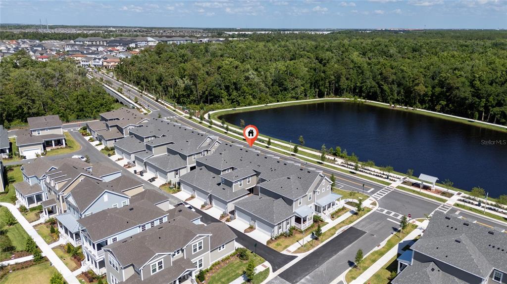 An aerial view shows a row of townhouses next to a pond and forest — 2408 CELEBRATION BOULEVARD, KISSIMMEE, FL