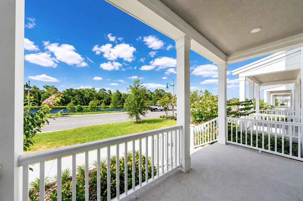 A covered porch with white railings overlooks a grassy lawn, a road, and a pond — 2408 CELEBRATION BOULEVARD, KISSIMMEE, FL