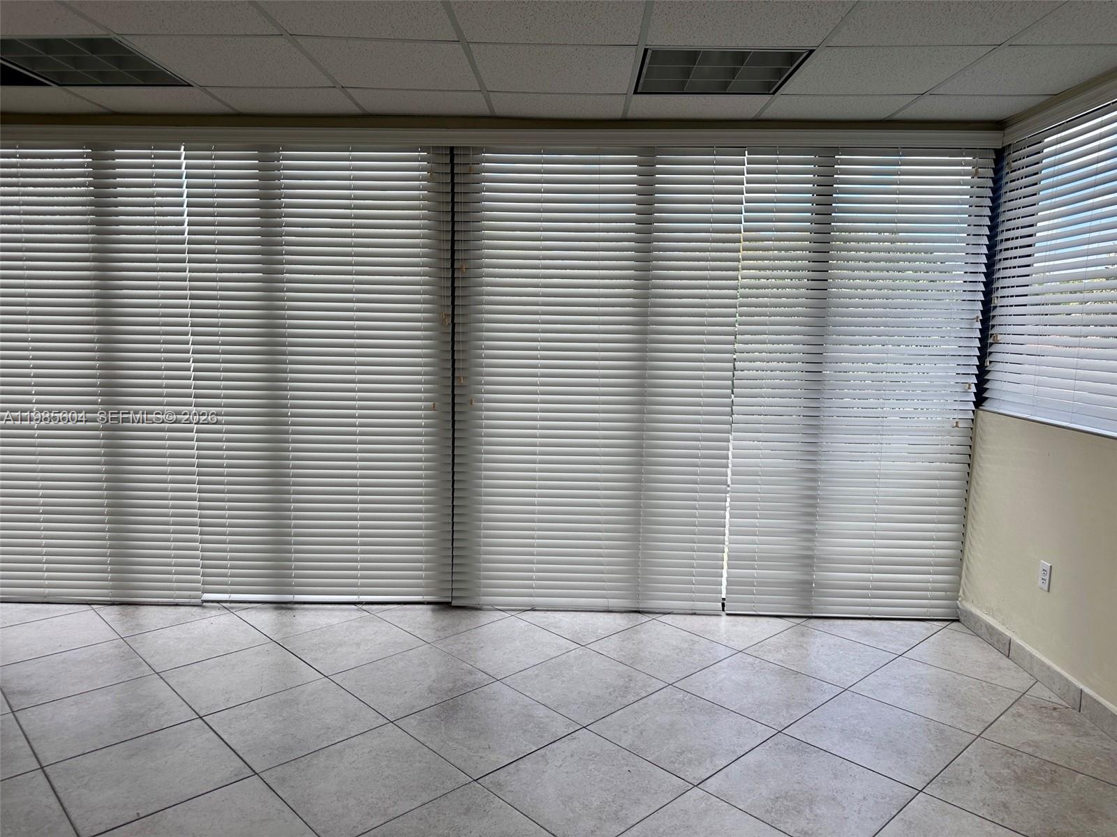 A room with light-colored tile flooring and large windows covered by horizontal blinds — 5455 SW 8 ST # 200, Miami FL 33134, MIAMI, FL