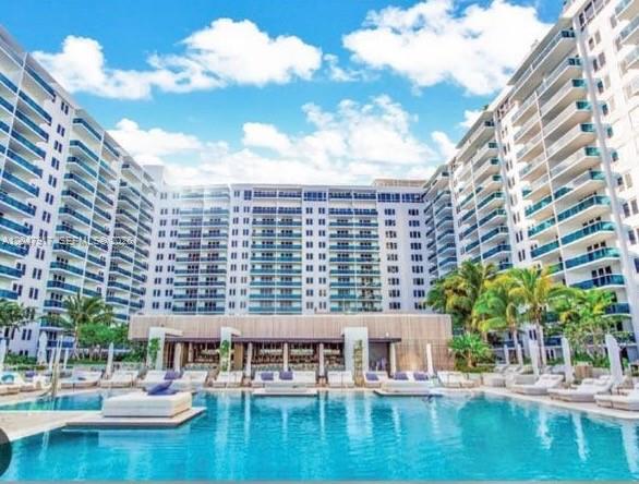 A large swimming pool sits in front of a multi-story apartment building with balconies — 2301 Collins Ave # 833, Miami Beach FL 33139, MIAMI BEACH, FL