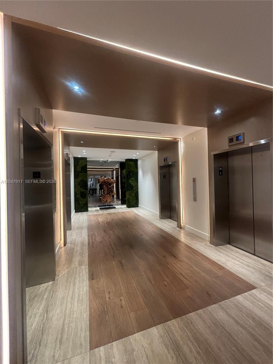 A modern elevator lobby features wood-look flooring, recessed lighting, and vertical green wall accents — 2301 Collins Ave # 833, Miami Beach FL 33139, MIAMI BEACH, FL