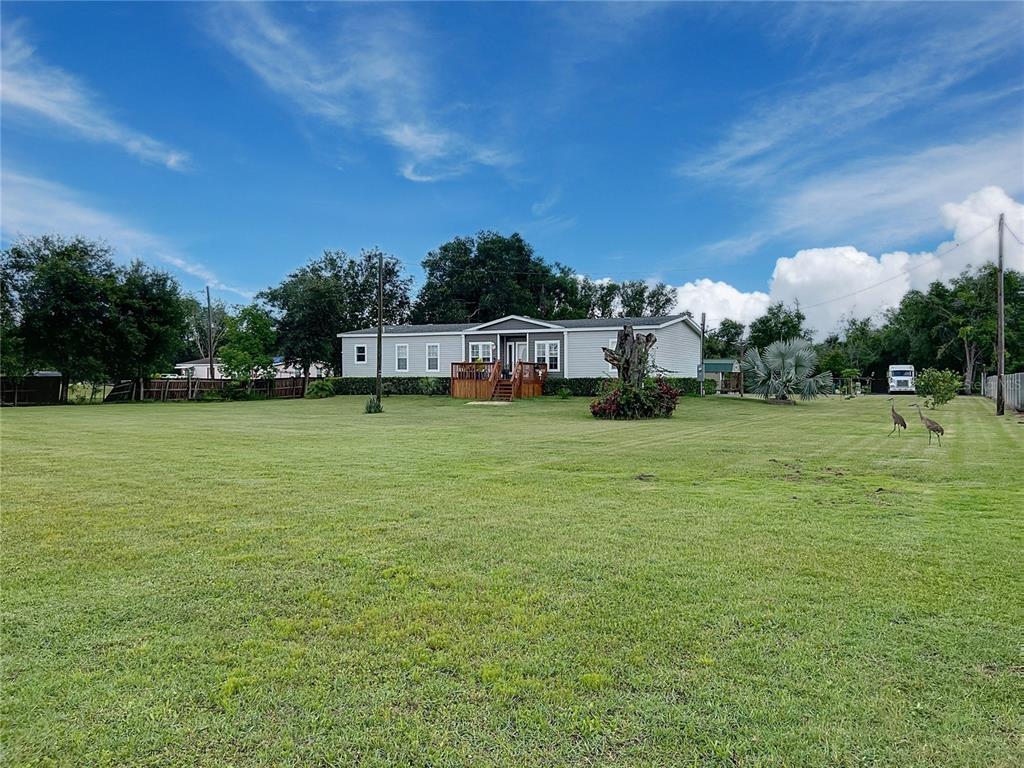A light-colored manufactured home sits on a large, grassy lot under a blue sky — 3710 KANDY LANE, HAINES CITY, FL
