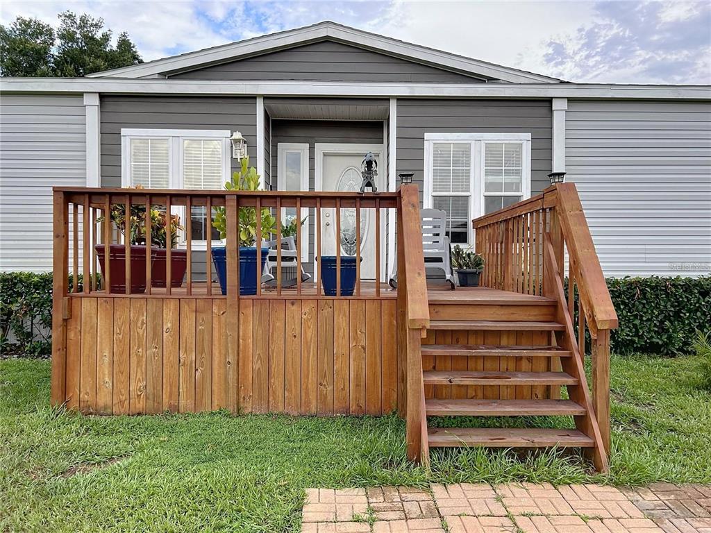 A wooden deck with stairs leads to the front entrance of a manufactured home — 3710 KANDY LANE, HAINES CITY, FL