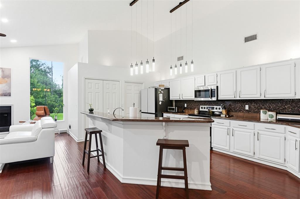 A kitchen with white cabinets, dark countertops, and a breakfast bar with two wooden stools — 114 SHADOWCREEK WAY, ORMOND BEACH, FL