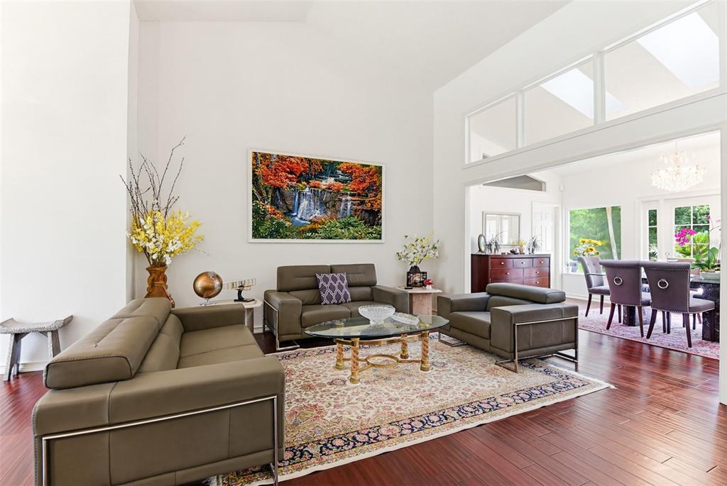 A living room with high ceilings, leather furniture, a patterned rug, and hardwood floors — 114 SHADOWCREEK WAY, ORMOND BEACH, FL