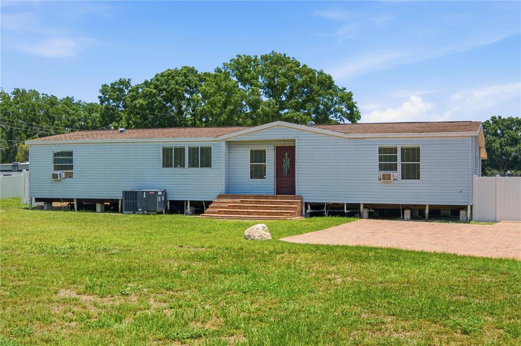 A single-story manufactured home with light blue siding, a brown roof, and brick front steps — 6502 FIVE ACRE ROAD, PLANT CITY, FL