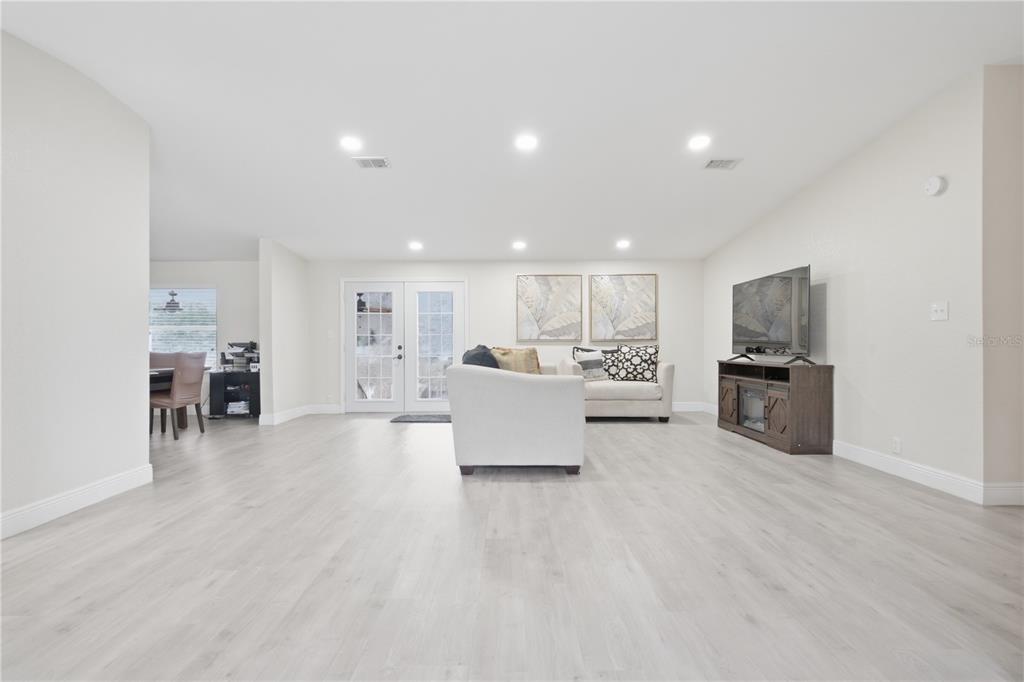 A bright living room features light wood-look flooring, recessed lighting, white walls, and a television console — 6502 FIVE ACRE ROAD, PLANT CITY, FL