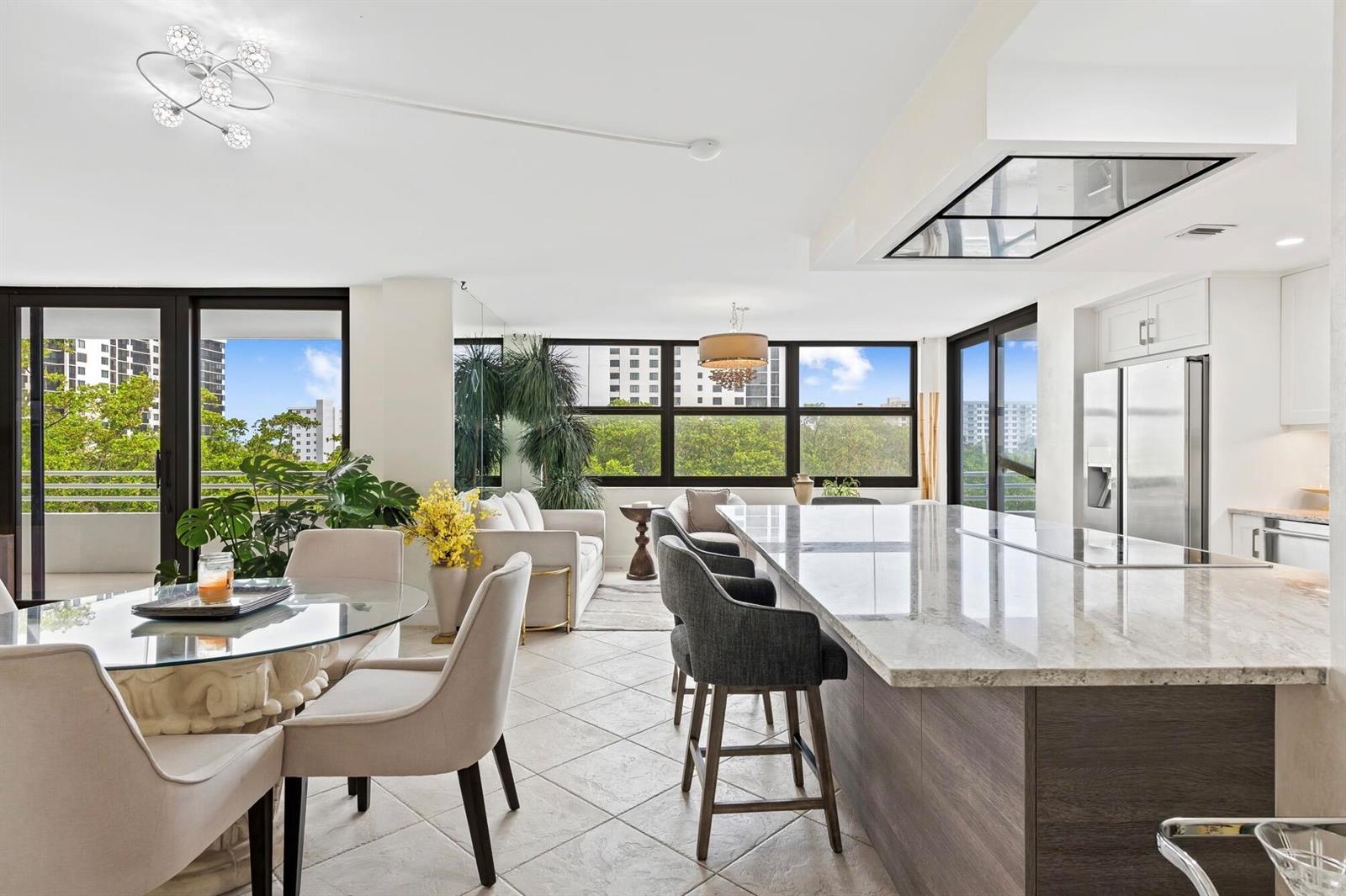A bright open-concept kitchen and dining area features a large stone island and balcony views — 3450 S Ocean Boulevard # 505, Highland Beach FL 33487, HIGHLAND BEACH, FL