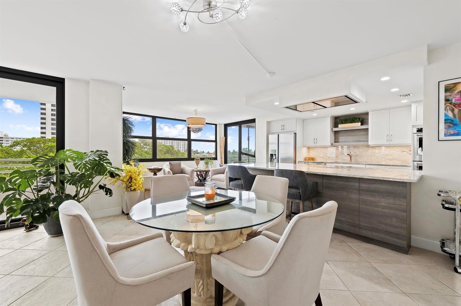 A bright open-concept kitchen and dining area features a glass table, island, and large windows — 3450 S Ocean Boulevard # 505, Highland Beach FL 33487, HIGHLAND BEACH, FL