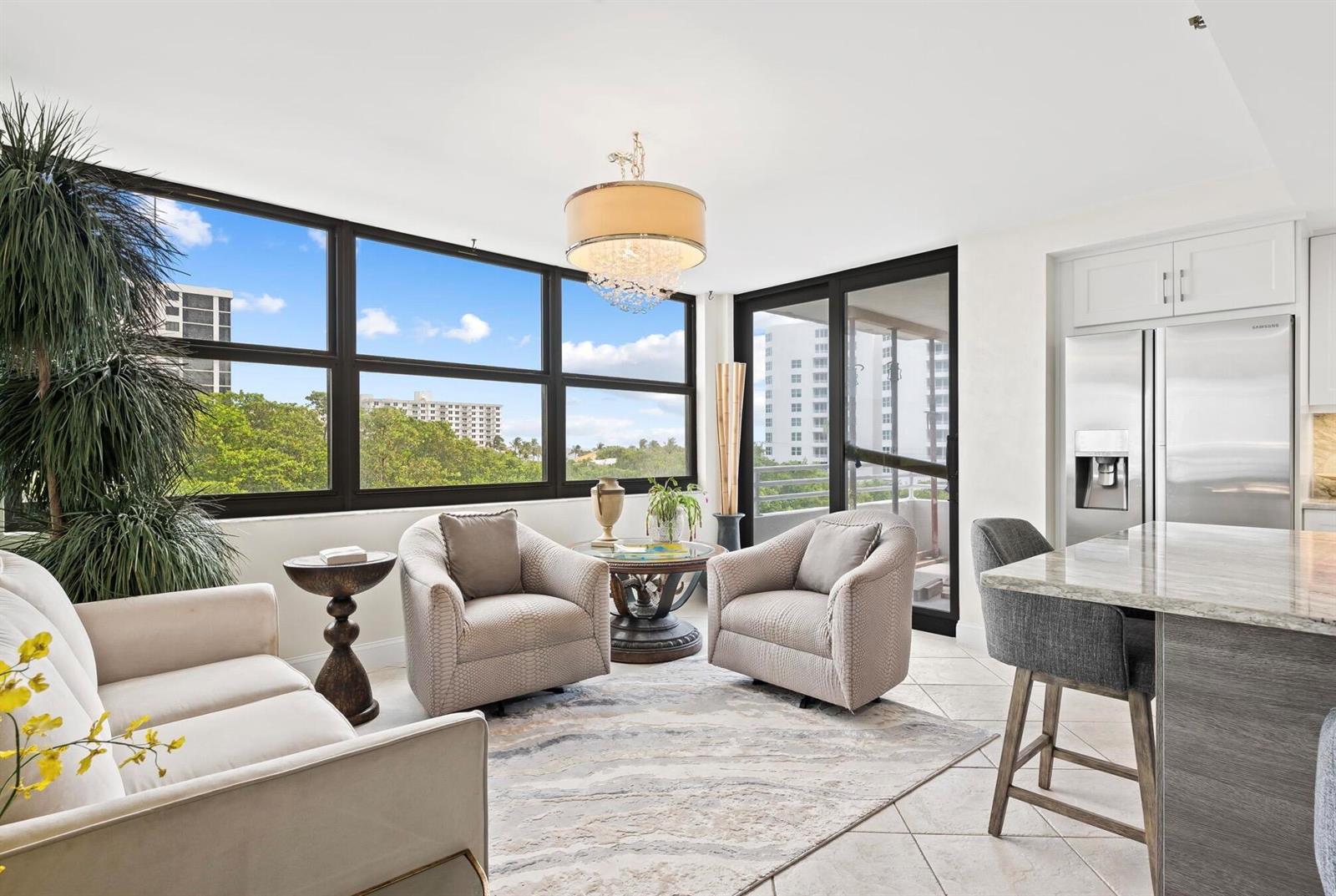 A living area with two armchairs, a sofa, a chandelier, and a kitchen island — 3450 S Ocean Boulevard # 505, Highland Beach FL 33487, HIGHLAND BEACH, FL