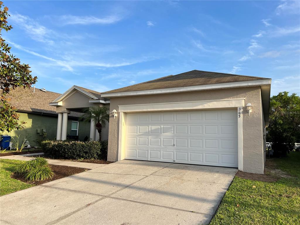 A single-story house with a beige stucco exterior and a two-car garage — 365 JAMES CIRCLE, LAKE ALFRED, FL