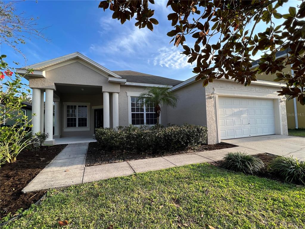 A single-story house with a beige stucco exterior, a two-car garage, and a covered entryway — 365 JAMES CIRCLE, LAKE ALFRED, FL