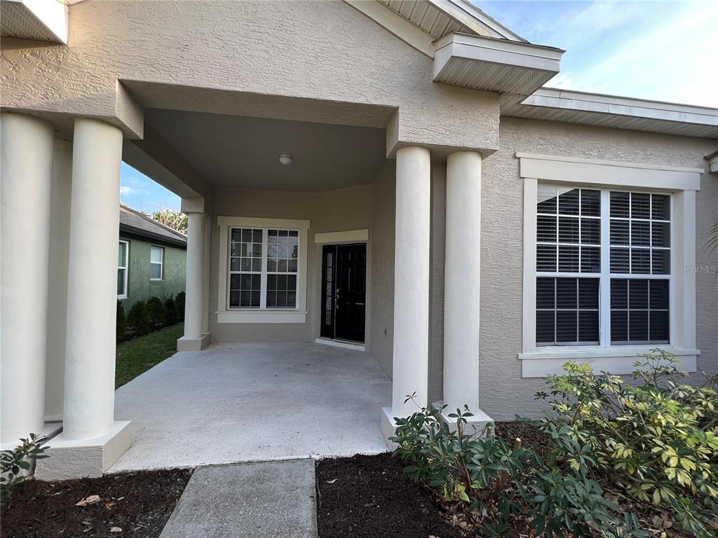 A covered front porch with white columns leads to a black front door — 365 JAMES CIRCLE, LAKE ALFRED, FL