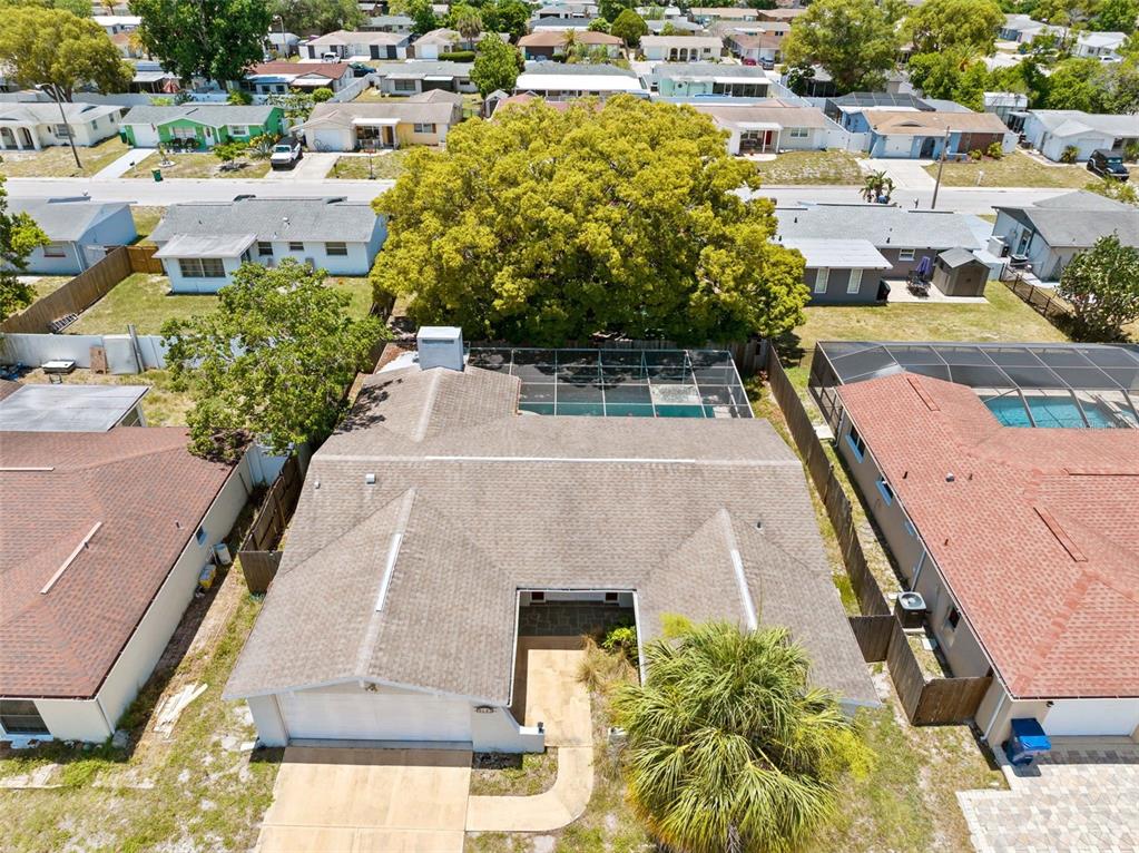 An aerial view shows a single-story house with a shingled roof, pool enclosure, and driveway — 9131 HUNT CLUB LANE, PORT RICHEY, FL