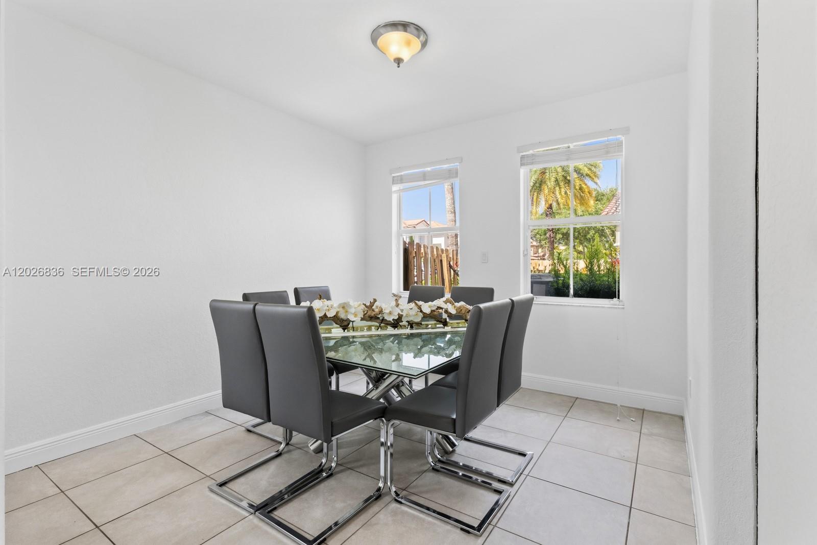 A dining room features a glass-topped table, six gray chairs, and tile flooring — 8610 NW 110th Ave, Doral FL 33178, DORAL, FL