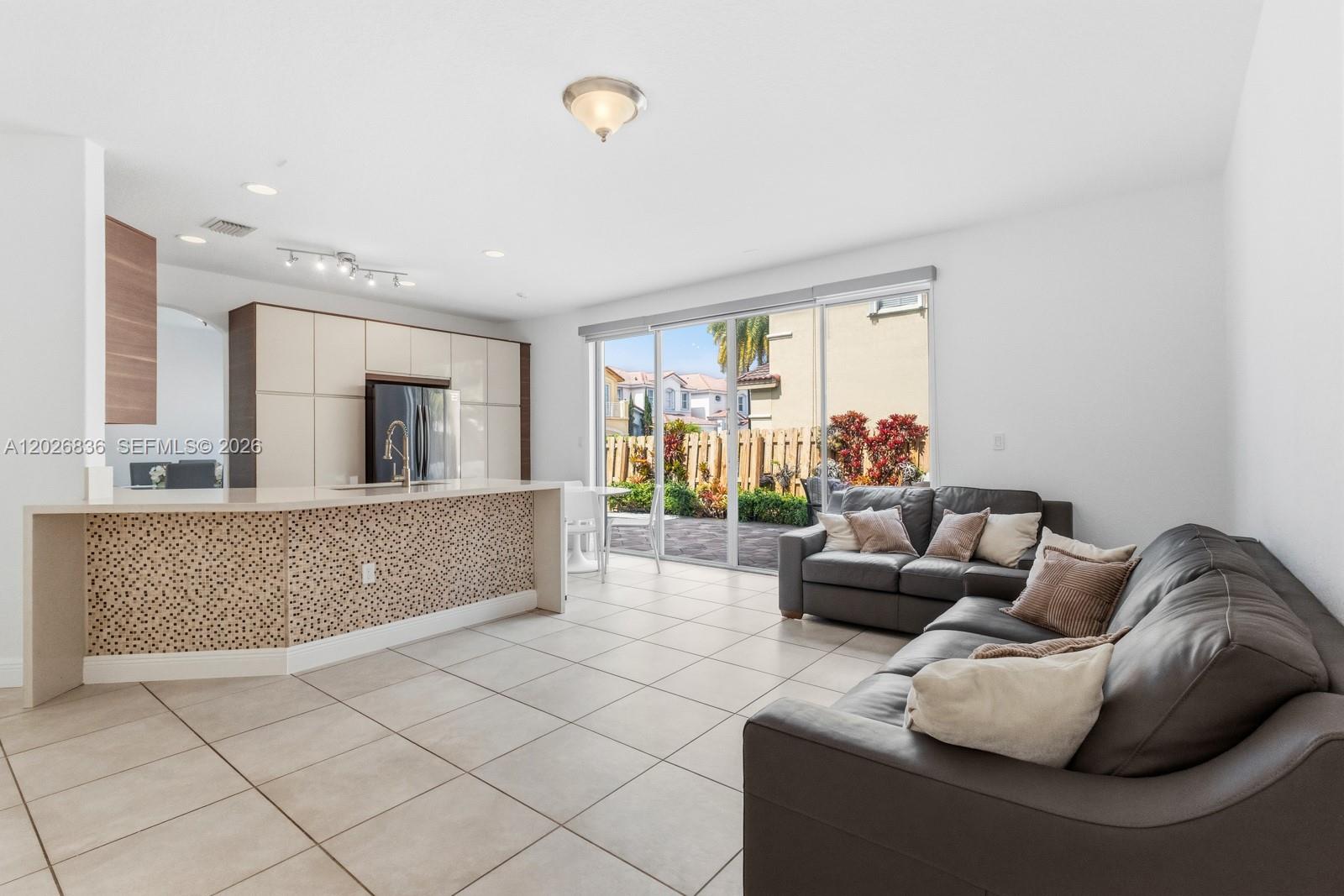 A kitchen with a mosaic-tiled island opens into a living area with tile flooring — 8610 NW 110th Ave, Doral FL 33178, DORAL, FL