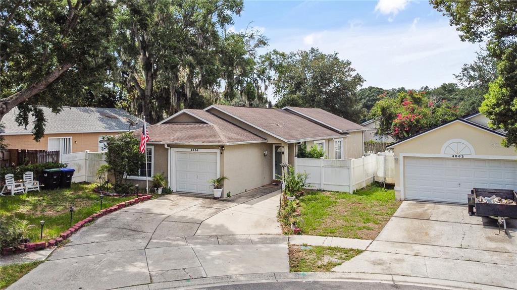 A single-story house with a white garage door, a concrete driveway, and a front lawn — 4856 ROBBINS AVENUE, ORLANDO, FL