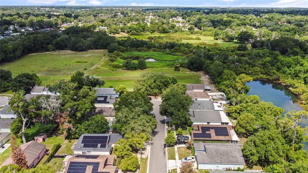 An aerial view shows a suburban street lined with houses, many featuring rooftop solar panels — 4856 ROBBINS AVENUE, ORLANDO, FL