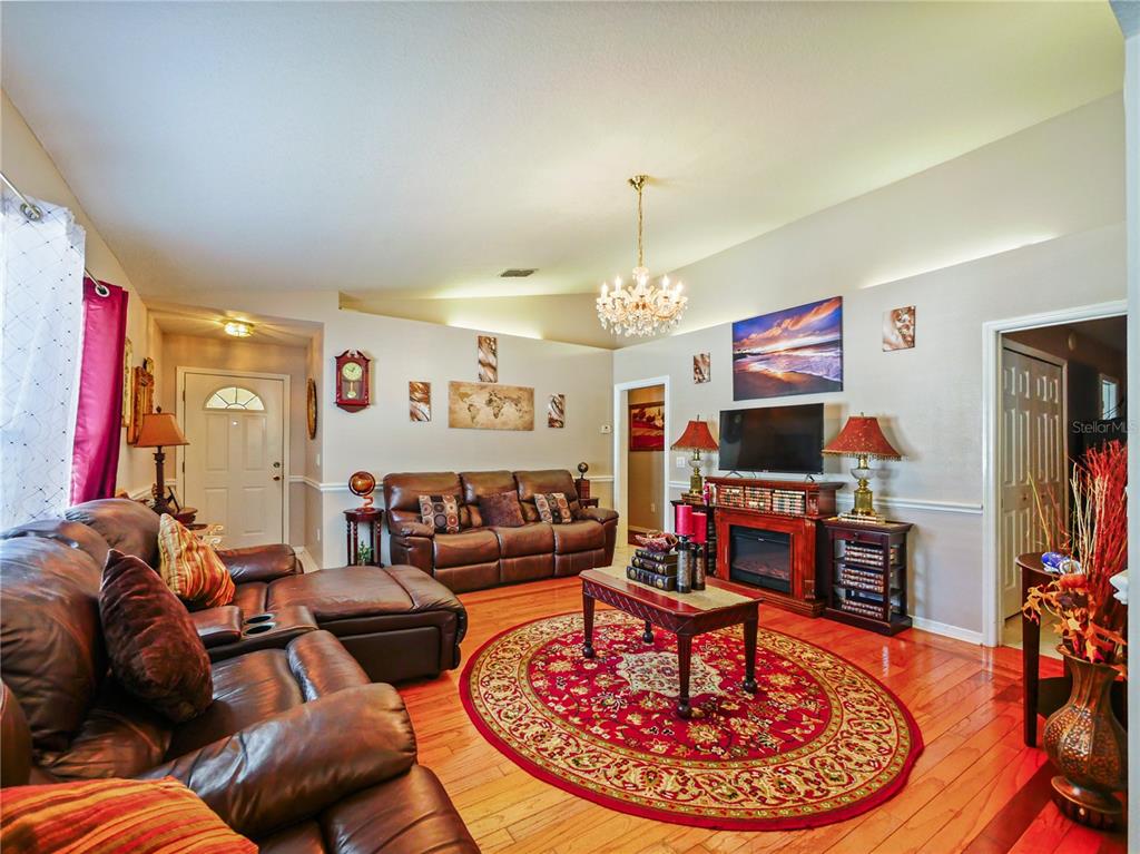 A living room features leather furniture, a red circular rug, and a fireplace with television — 4856 ROBBINS AVENUE, ORLANDO, FL